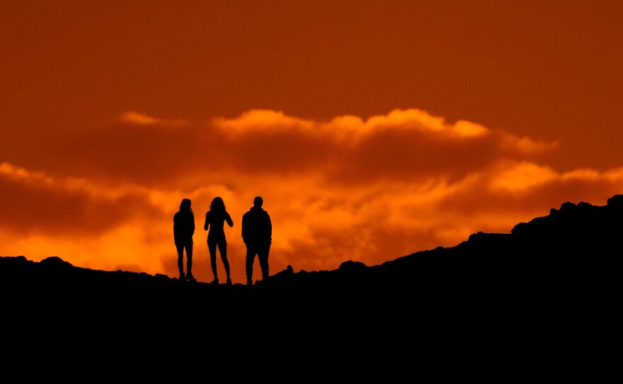 Hikers are silhouetted against the sky as they view the sunset from a ridge at Papago Park, Thursday, March 2, 2023, in Phoenix.