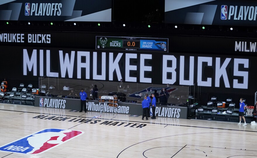 Officials stand beside an empty court at the scheduled start of an NBA basketball playoff game between the Milwaukee Bucks and the Orlando Magic, Wednesday in Lake Buena Vista, Fla. The Bucks didn't take the floor in protest against racial injustice and the shooting of Jacob Blake, a Black man, by police in Kenosha, Wisconsin.