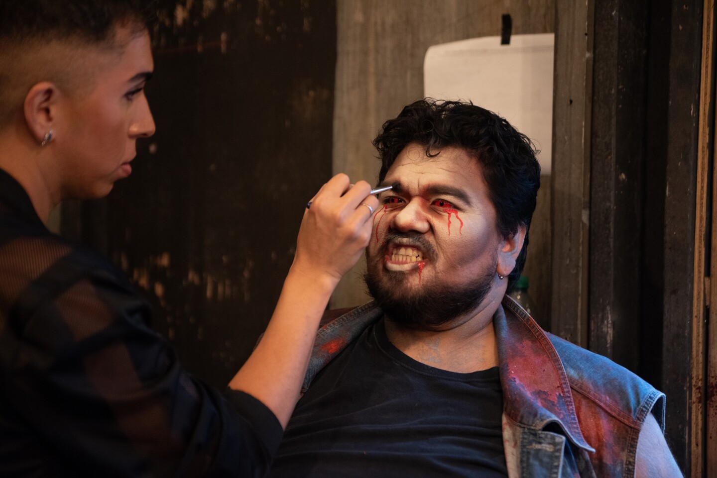 Makeup artist J.J. Jimenez accentuates scare actor Ricardo Aguilera's red eyes at The Haunted Trail in Balboa Park on Sept. 25, 2025.