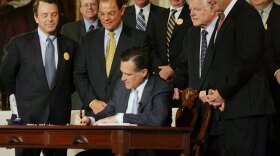 <p>Massachusetts Gov. Mitt Romney signs into law a new health care bill on April 12, 2006, in Boston. The late Sen. Ted Kennedy peers over his shoulder. </p>