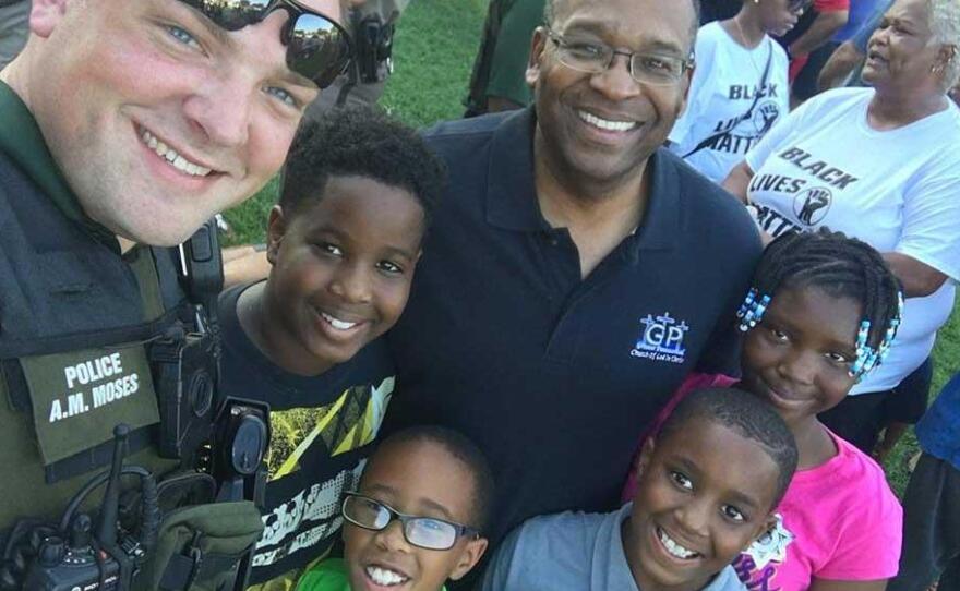 A Wichita police officer poses with residents at the First Steps Community Cookout on Sunday.