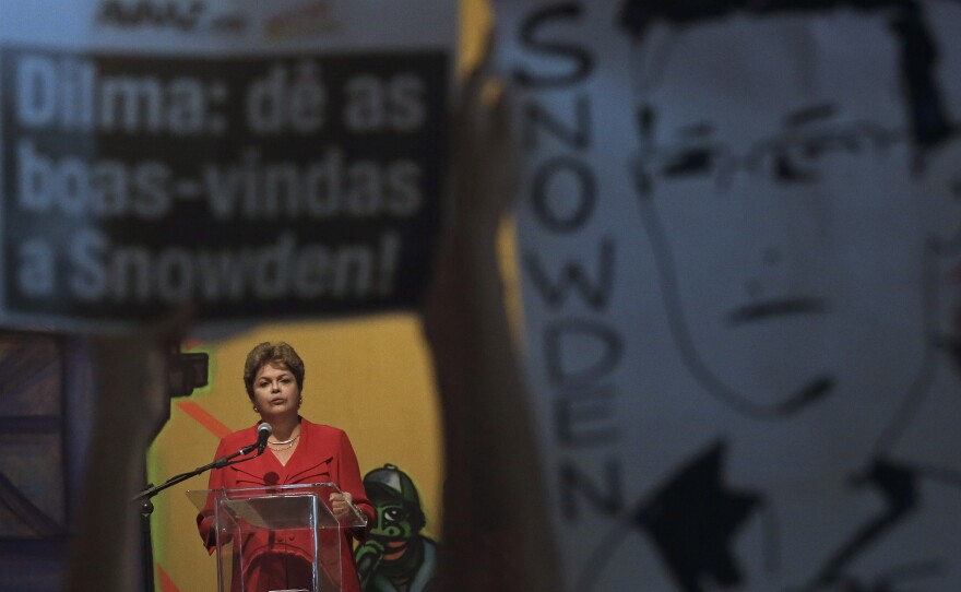 Brazil's President Dilma Rousseff speaks in Sao Paulo on Dec. 19, framed by posters held by protesters calling for asylum for National Security Agency leaker Edward Snowden.