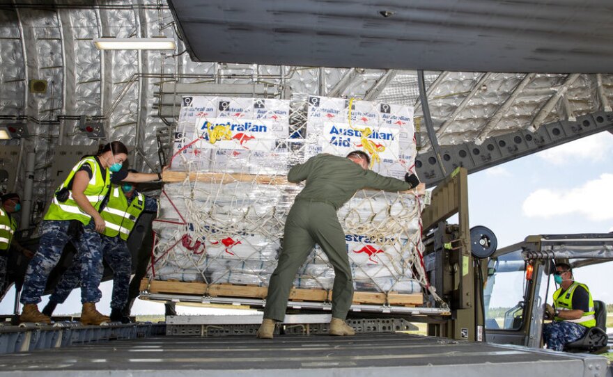 In this photo provided by the Australian Defence Force, personnel unload emergency aid supplies at Tonga's Fuaʻamotu International Airport, near Nukuʻalofa, Thursday, Jan. 20, 2022, after a volcano eruption.