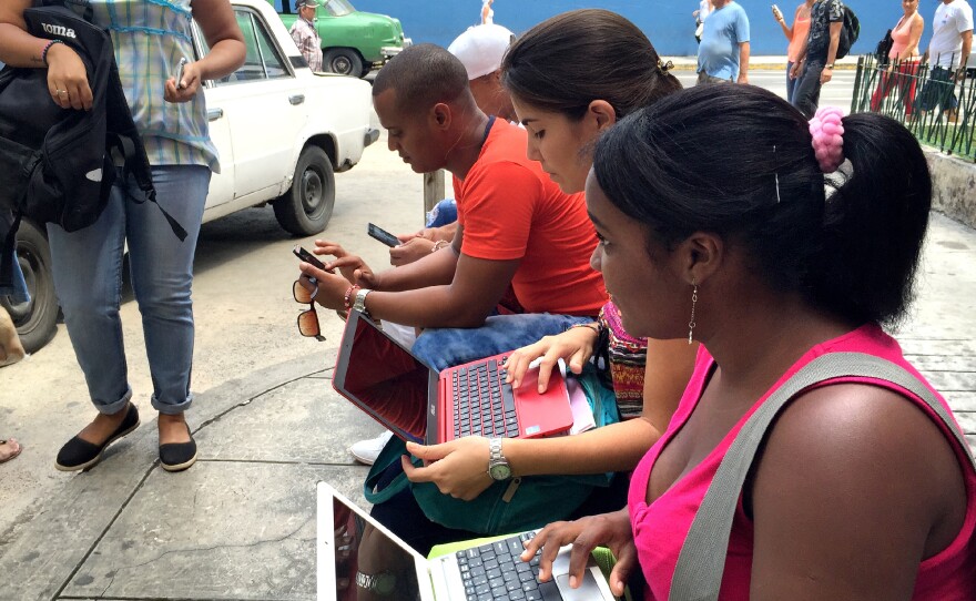 Havana residents huddle in front of the Habana Libre hotel, trying to log onto the Internet.
