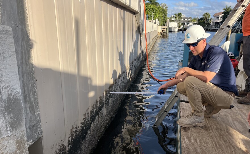 Arthur Tiedeman measures the distance between scumline and the seawall's top to determine where to put the planters.