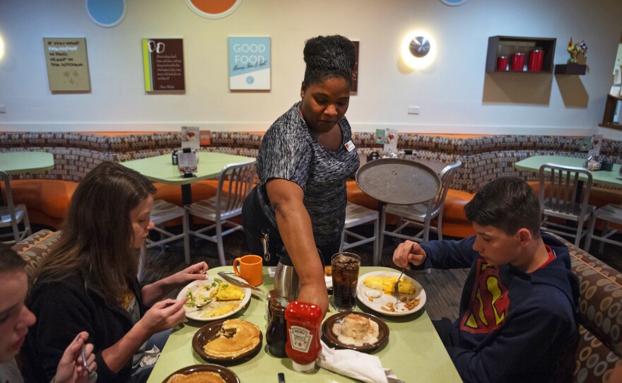 Tanisha Cortez waits on a table at a restaurant in Ames, Iowa. When the previous restaurant she worked for closed, Cortez applied to others and had job offers right away. Jobs are plentiful in Ames, a small city of more than 65,000 residents tucked amid farm fields north of Des Moines.