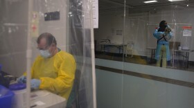 Registered nurse Leslie Clark, right, collects a nasal swab sample from a man as administrative worker Sander Edmondson works on his computer at a COVID-19 testing site in Los Angeles, Sunday, Dec. 27, 2020. 