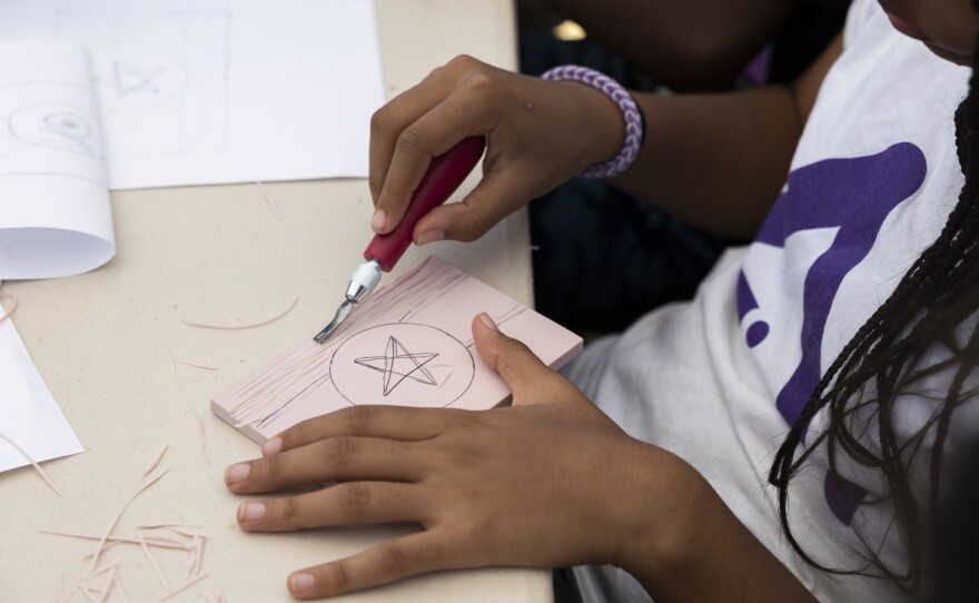 In an art activity, Tewa carves an Ethiopian flag: the country she was born in.