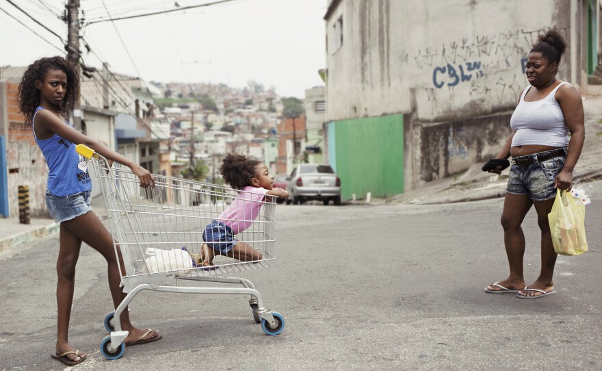 Maysa, left, her little sister Luana and mother Ana on a street in Sao Paulo. They just returned from buying bread for Sunday morning breakfast.