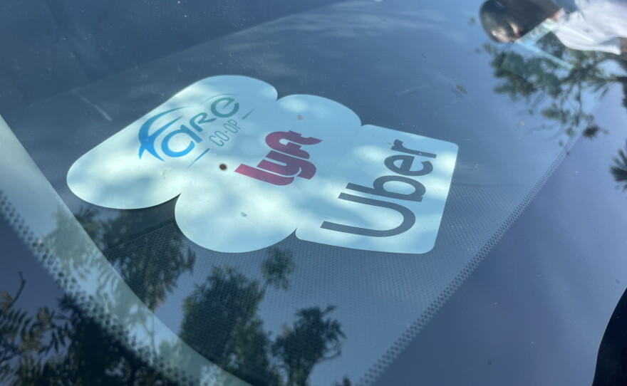 Rideshare logo cutouts are seen on the dash of rideshare driver and co-founder of San Diego Drivers United Librado Rivera's work car, Aug. 10, 2026.