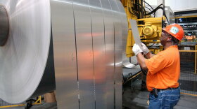 An employee inspects finished rolls of aluminum at an Alcoa facility in Newburgh, Ind., in 2006. The company has slashed payrolls in its core business by about one-third.