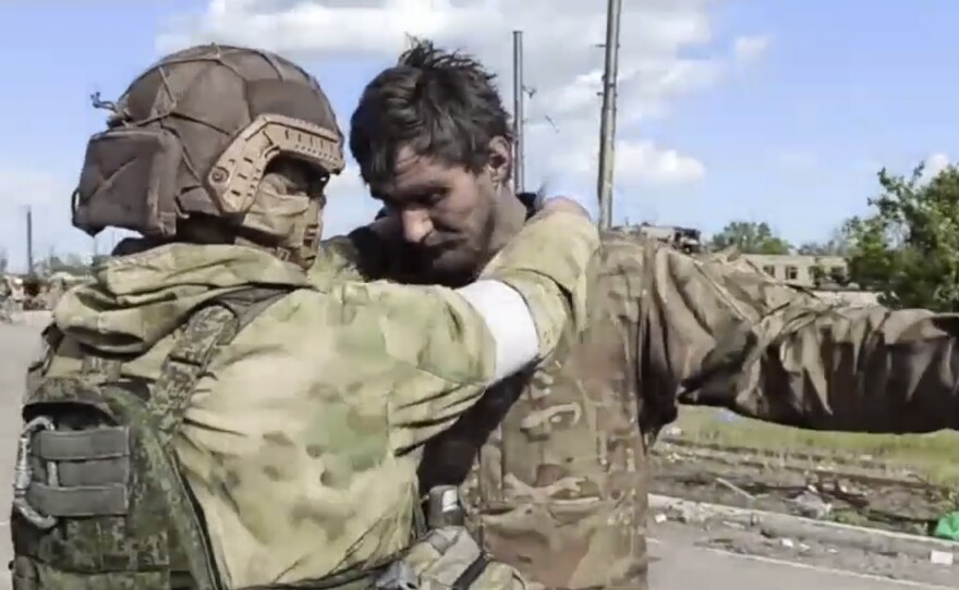 In this photo taken from video released by the Russian Defense Ministry on Friday, May 20, 2022, a Russian serviceman frisks a Ukrainian serviceman after they leaved the besieged Azovstal steel plant in Mariupol, in territory under the government of the Donetsk People's Republic, eastern Ukraine.