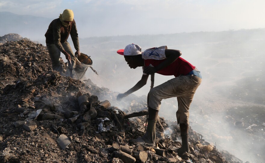 At the city landfill, men look for metal near the edge of a pit that used to be full of raw sewage. Construction delays at the Titanyen sewage treatment plant meant that raw sewage continued to be dumped at the landfill for months after the cholera epidemic began in 2010.