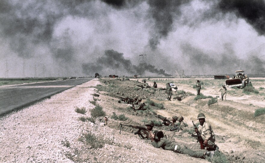 Iraqi troops are beside a roadway in Iran on Oct. 17, 1980. The smoke in the background is from fires along pipelines used to carry oil from the giant refinery at Abadan to Ahwaz and Tehran.