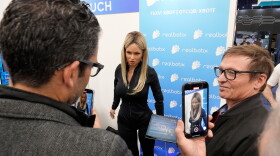 FILE - A Realbotix humanoid robot, center, speaks with attendees at a Realbotix booth during the CES tech show Jan. 8, 2025, in Las Vegas.