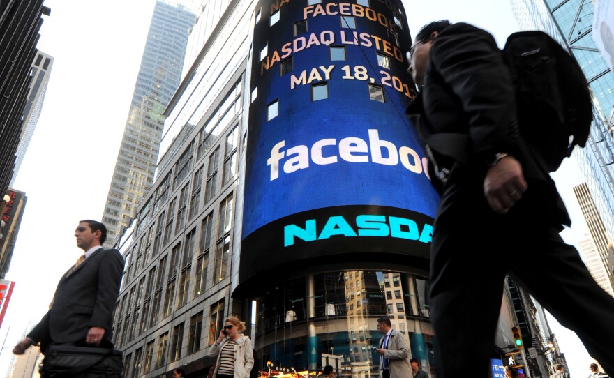 Pedestrians walk past the NASDAQ stock exchange in New York, May 18, 2012.