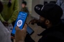 Several migrants in Tijuana's Palacio Municipal struggle to create a profile in the CBP One app. The Biden administration began requiring migrants seeking humanitarian protection in the U.S. to register through the app in January. Jan. 18, 2023.