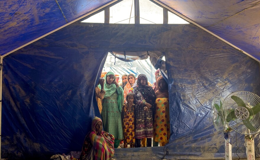 Dozens of women wait outside a pop-up clinic run by midwives in a tent encampment for families made homeless by Pakistan's unprecedented summer monsoon rains that caused widespread flooding.