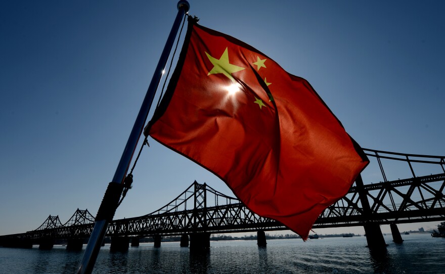 A Chinese flag flies on a boat next to the bridge that spans the Yalu River linking the North Korean town of Sinuiju with the Chinese town of Dandong. Most of North Korea's trade is with China, and much of it crosses the border here.