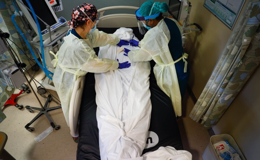 Nurse educator Katie Demelis and nurse manager Nydia White wrap the the body of a patient who died of COVID-19 at Mount Sinai South Nassau hospital in Oceanside, N.Y., on April 15, 2020.