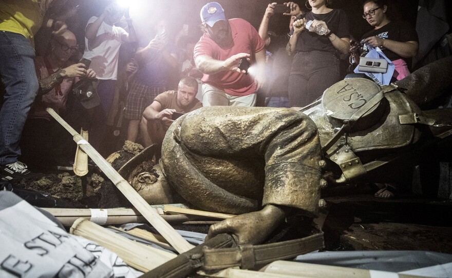 Demonstrators and spectators gather around the toppled Confederate statue known as Silent Sam in August 2018 at UNC-Chapel Hill in North Carolina. A judge has overturned a settlement that the UNC System made with the Sons of Confederate Veterans.