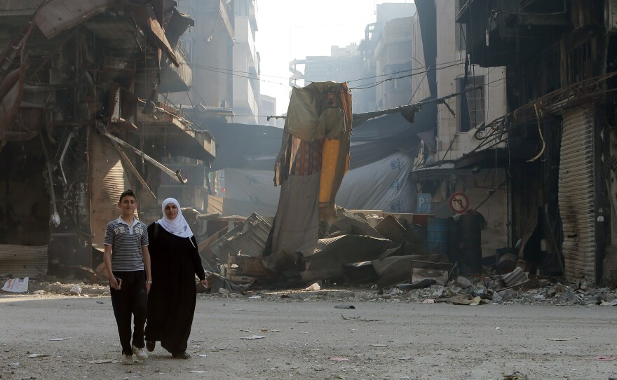 Syrians walk through a destroyed neighborhood in the city of Homs, on May 12. President Obama says he will be increasing aid to moderate Syrian rebels who have been battling President Bashar Assad's forces.