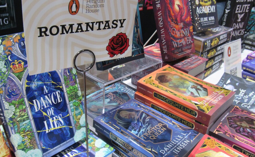 Piles of romantasy novels are seen at Comic-Con on July 25, 2025. The genre, which blends romance and fantasy, continues to draw new readers.