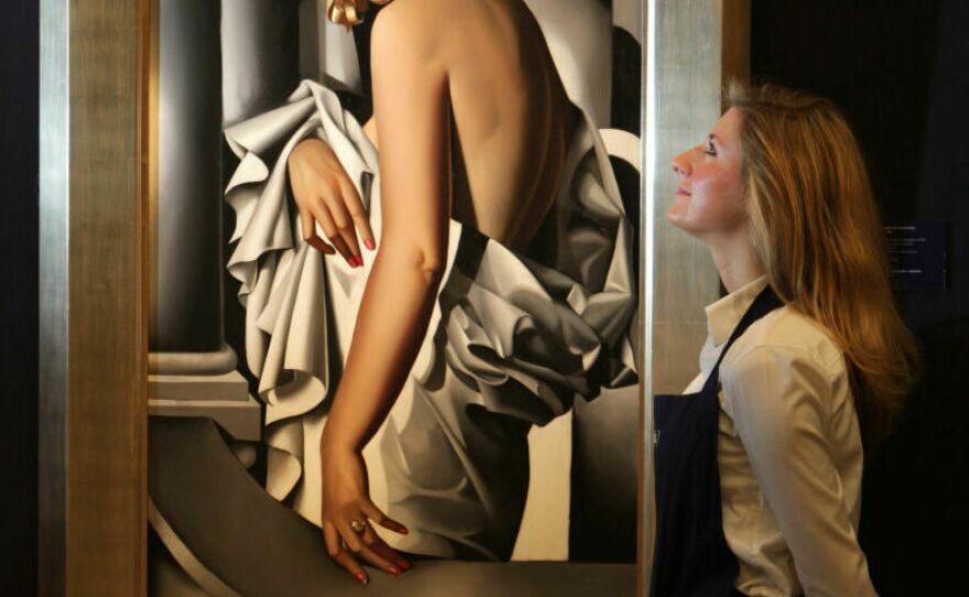 A gallery technician at Sotheby's auction house admires a painting by Tamara de Lempicka in 2009 entitled <em>Portrait de Marjorie Ferry</em> from 1932.