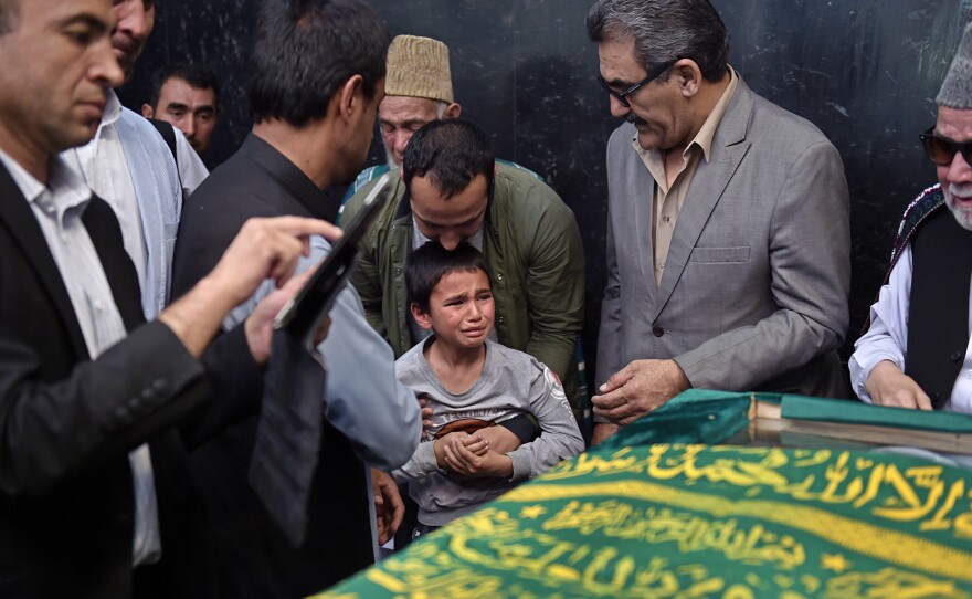 Ten-year-old Mustafa (center), son of Afghan reporter Zabihullah Tamanna, prays with relatives and friends next to the coffin during Tuesday's ceremony.