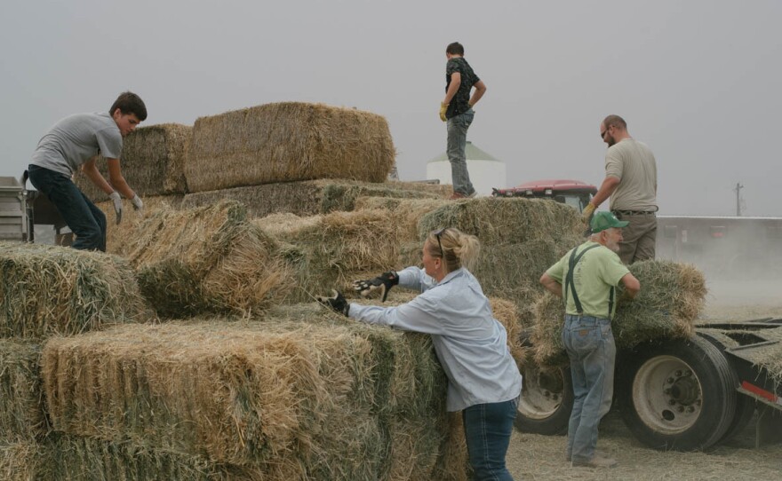 People offload donated hay from a flatbed truck in the lot of the Tech Feed Store in Omak, Wash. The Andrews family's store has been a hub for donations and communications for local ranchers during the Okanogan Complex fires.