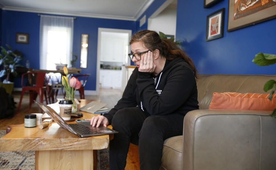 Alison Dreith puts her head in her hand as she realizes she has to turn away a client from Texas, while working from home on Thursday, April 14, 2022, in southern Illinois. Dreith works remotely for the Midwest Access Coalition, which pays for "practical support" for women seeking abortions. That includes things like air fare, gas money, hotel rooms or child care. High demand from women in Texas, which has restricted abortion, has caused MAC to have to send those clients to other support organizations. "It's sad," she says. "It just breaks your heart when you feel like you're the ones set up to take care of them and then you can't…. We need help."