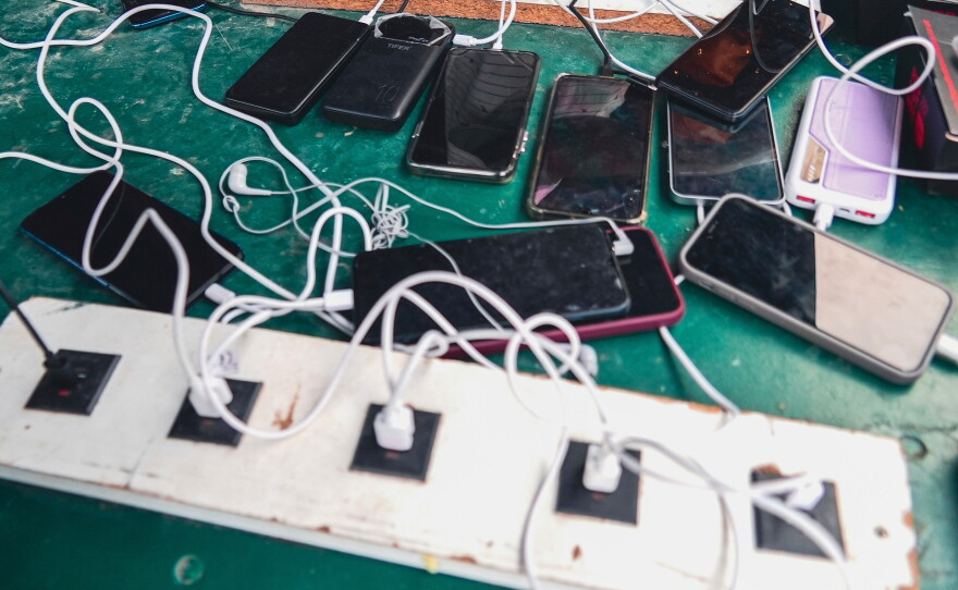 FILE - Phones are kept for charging at a Doctors Without Borders informal camp in Mardyck, northern France, Wednesday, July 2, 2025.