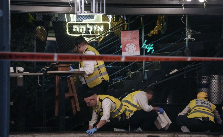 Members of Israeli Zaka Rescue and Recovery team clean blood from the site of a shooting attack In Tel Aviv on Thursday.