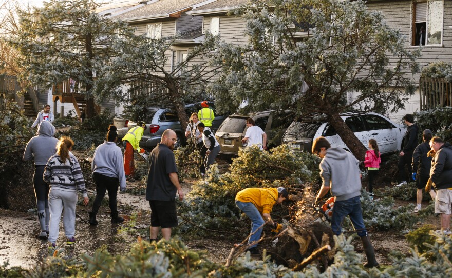 Cleanup begins after a tornado touched down in Coralville, Iowa, on Friday. City crews, residents and neighbors worked to clear debris off the roadway and vehicles.