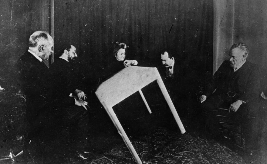 A table appears to move of its own accord during a seance in Paris in 1900.