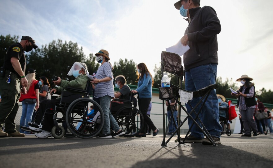 People lined up to receive the COVID-19 vaccine at a mass vaccination site in Disneyland's parking lot in Anaheim, Calif. on Jan. 13. The state says all residents 65 or older are now eligible to receive the vaccine.