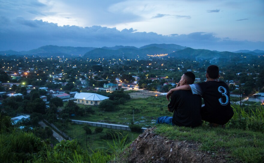 Moises, 17, left, and Jaime look down on the patchwork of neighborhoods outside San Pedro Sula, a city in Honduras where gang rivalries play out. The violence is so bad that "no one goes in" the neighborhoods, says photojournalist Tomas Ayuso. "Food delivery trucks, ambulances don't want to go in because they're afraid something will happen."
