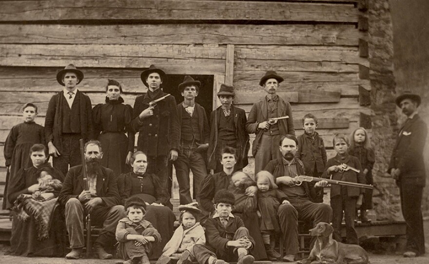 William Anderson Hatfield, known as "Devil Anse," his wife Levisa “Levicy” Hatfield, and several of their children pose with weapons, 1897.