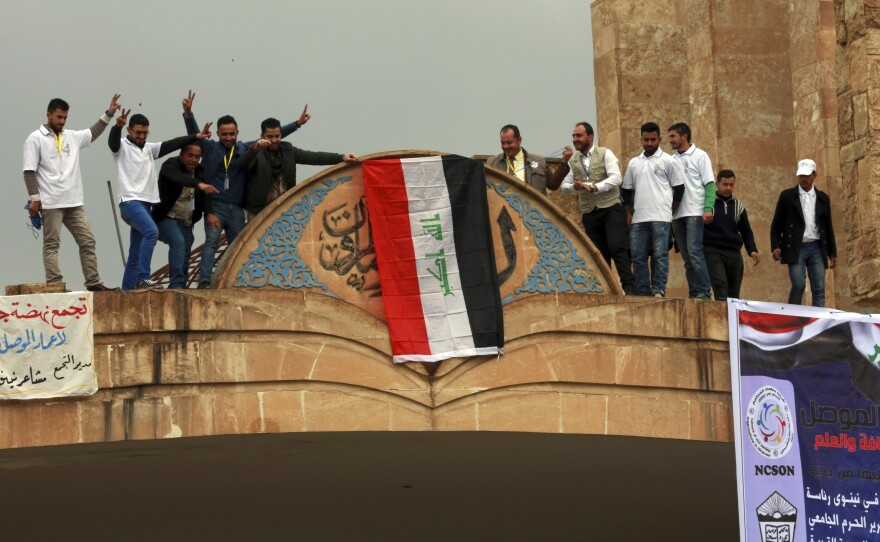 Students at Mosul University place the Iraqi national flag at the entrance on Sunday after it was liberated from Islamic State militants. The Iraqi military, supported by the U.S., has retaken the eastern part of the city. ISIS still holds the western part of Mosul, its last major stronghold in Iraq.