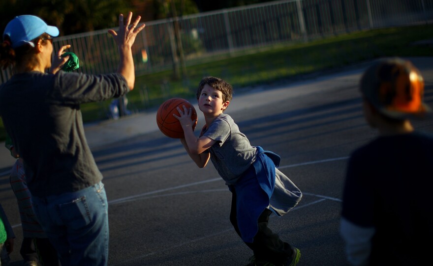 Henry Condes, 7, practices shooting a basketball. His mother, Yvonne, spends most afternoons ferrying her two boys from one sporting activity to another.