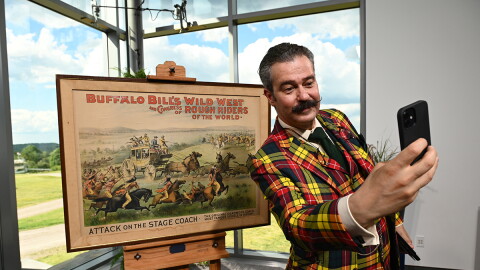 Nicholas Lowry appraises a Buffalo Bill Attack on the Stage Coach poster, ca. 1893, in Shelburne, VT. 
