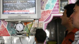 Iraqis follow a June 14 parliamentary session on local TV at a barbershop in Baghdad.