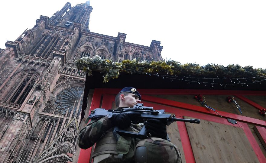 A French soldier stands guard at the Christmas market in Strasbourg, in front of the city's cathedral, as police conduct a search for a man suspected of opening fire on a crowd the night before.