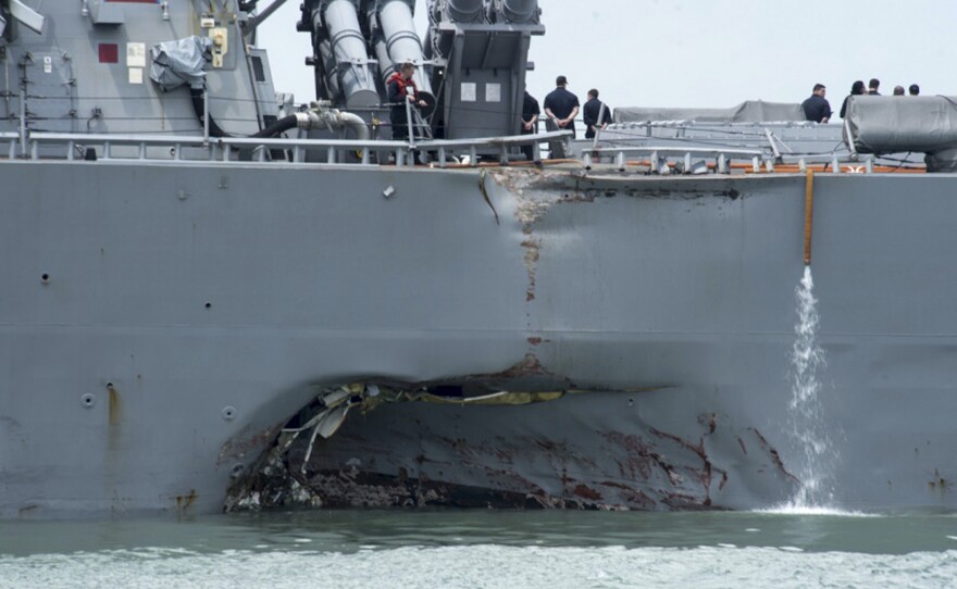 Damage to the USS John S. McCain is visible as the guided-missile destroyer steers toward Changi naval base in Singapore following a collision with the merchant vessel Alnic MC in August.