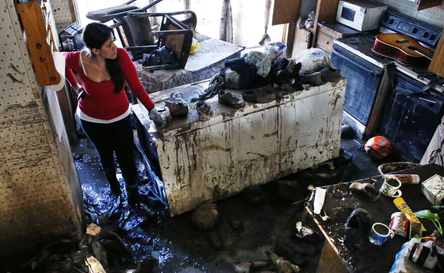 Sonia Marquez, an organizer with the Colorado Immigrant Rights Coalition, looks for keepsakes amid the muck inside one of the many flood-ravaged homes at a decimated trailer park in Evans, Colo., on Sept. 24. The majority of the residents in the trailer park are immigrants.