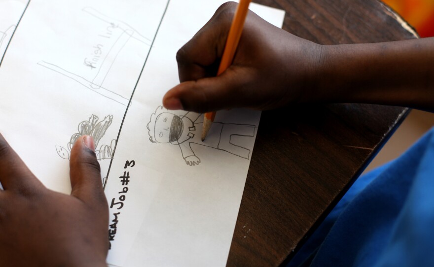 Robert Taylor, 11, draws a doctor as his dream job during a brainstorming session with mentor Maurice Kie. His two brothers are also in the program.