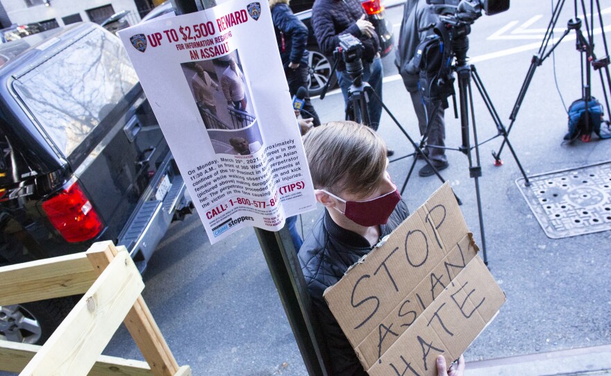A man holds a sign at an Asian American anti-violence press conference on Tuesday, outside the building where a 65-year-old Asian woman was physically and verbally attacked in New York City. Police said Wednesday that Brandon Elliot, 38, had been arrested and charged with crimes which include assault as a hate crime.