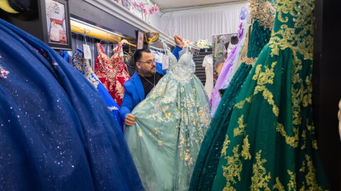 Osmar Naranjo hangs a quinceañera gown on a rack of gown in his shop Cynderella Brides in Chula Vista, April 30, 2026.