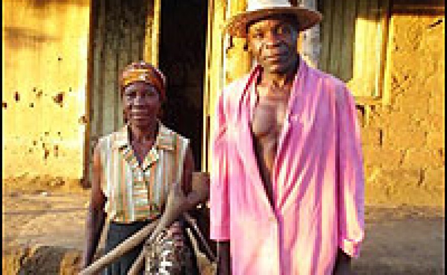 Faison and Betty Phiri stand in front of their home.  Faison Phiri hopes to replace the crumbling plaster and leaky corrugated iron roof one day.