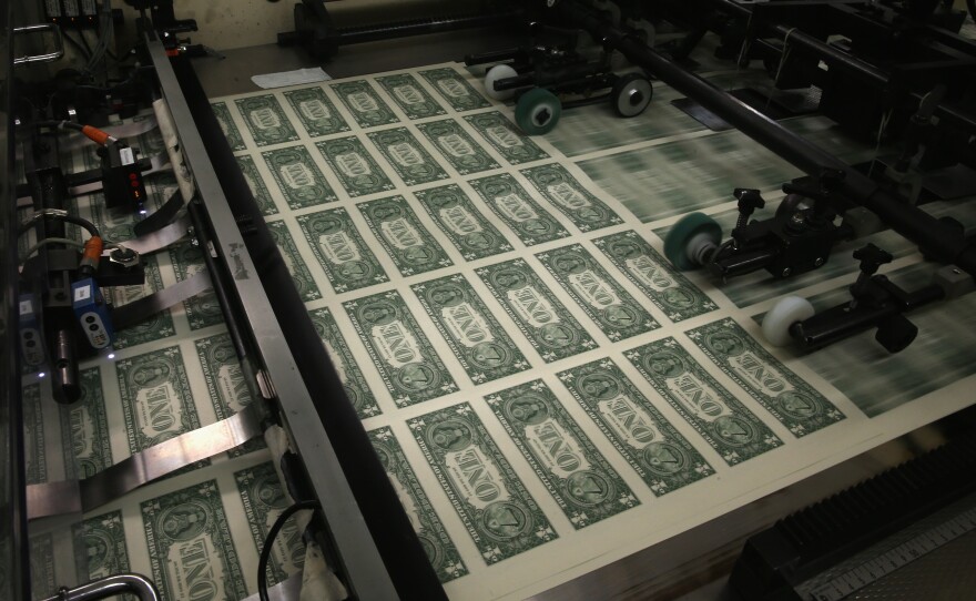 Sheets of one-dollar bills run through the printing press at the Bureau of Engraving and Printing on March 2015 in Washington, D.C. National debt is expected to reach an all-time high of 107% of GDP in 2023.